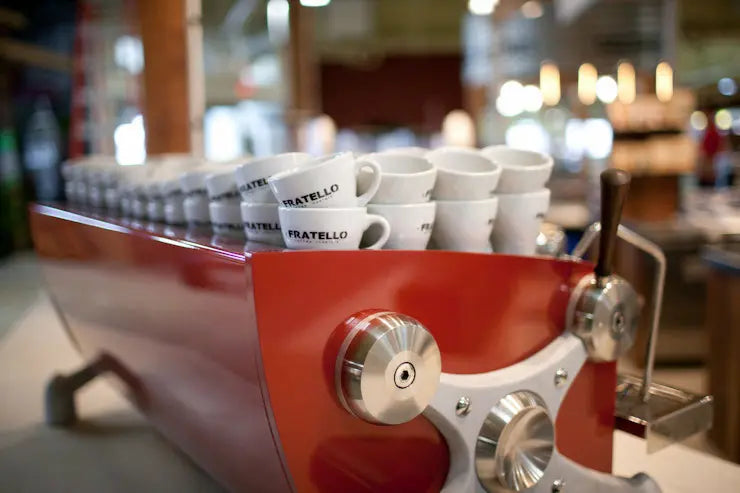 Red Slayer espresso machine with stacked Fratello-branded cups in a cafe